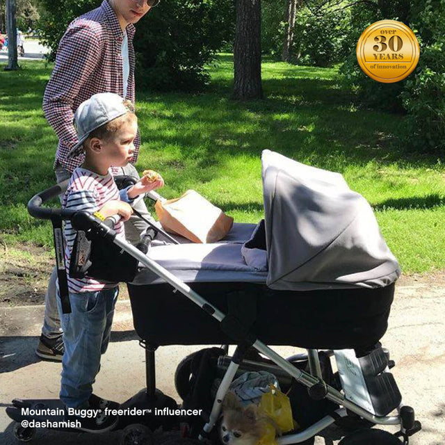 family strolling through park with toddler riding their freerider™ scooter board attached to rear of duet™ double pushchair - Mountain Buggy freerider™ influencer @dashamish