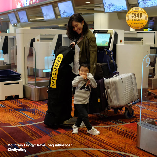 mother with toddler at the airport with luggage - Mountain Buggy travel bag influencer @kellynting