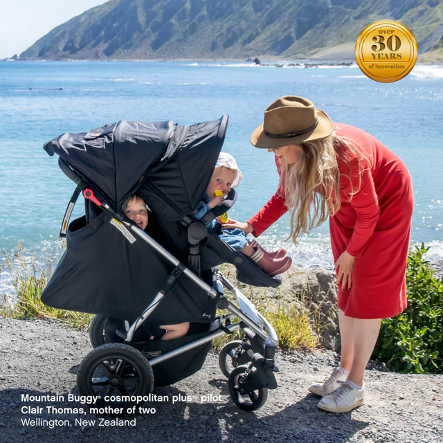 mother of two young kids dubbing in their cosmopolitan plus buggy, enjoying sunny day by near Red Rocks, Wellington, New Zealand - cosmopolitan plus™ pilot Clair Thomas - Mountain Buggy - fabric colour_black