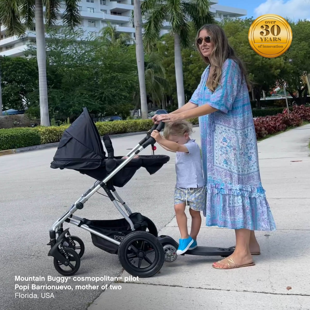 mother of two pushing cosmopolitan buggy in parent facing position with freerider scooter attached - Mountain Buggy cosmopolitan pilot Popi Barrionuevo, Florida, USA - fabric colour_black